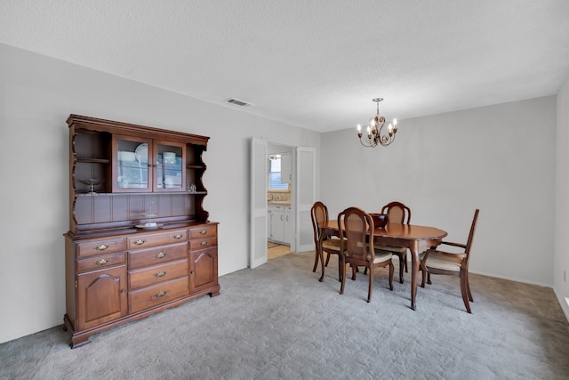 dining space featuring light carpet, a textured ceiling, and a chandelier