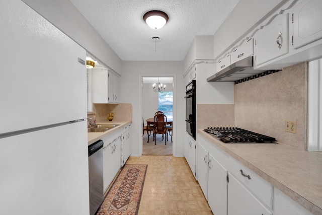 kitchen featuring stainless steel appliances, an inviting chandelier, a textured ceiling, white cabinets, and light parquet floors