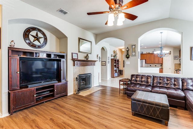 living room with vaulted ceiling, ceiling fan with notable chandelier, and wood-type flooring