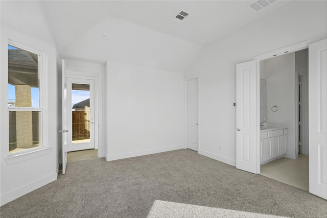 unfurnished bedroom with connected bathroom, light colored carpet, and vaulted ceiling