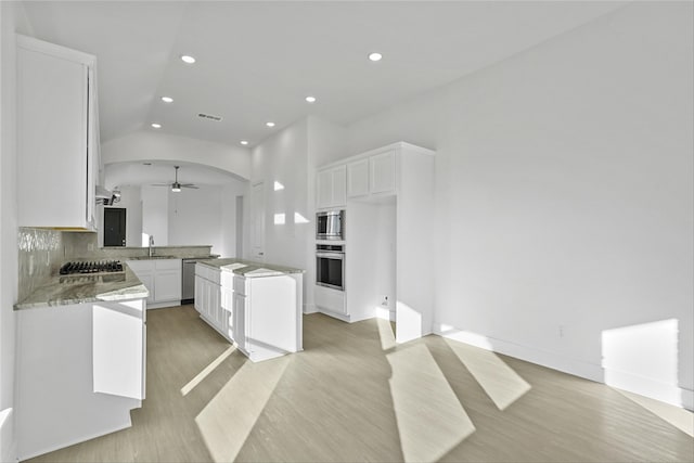 kitchen with white cabinetry, sink, stainless steel appliances, tasteful backsplash, and a kitchen island