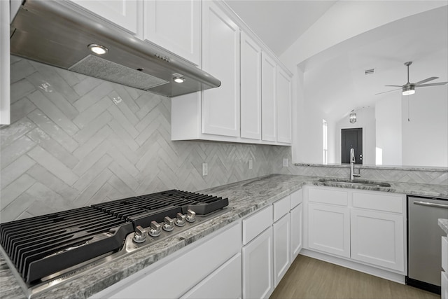 kitchen featuring lofted ceiling, white cabinetry, sink, and extractor fan