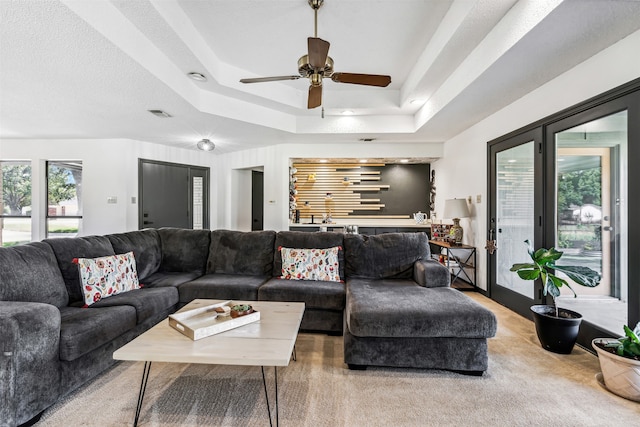 living room with a raised ceiling and ceiling fan