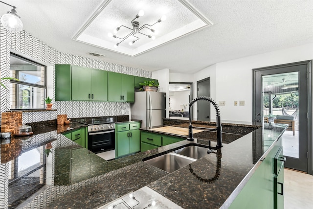 kitchen featuring a wealth of natural light, appliances with stainless steel finishes, green cabinets, and a textured ceiling