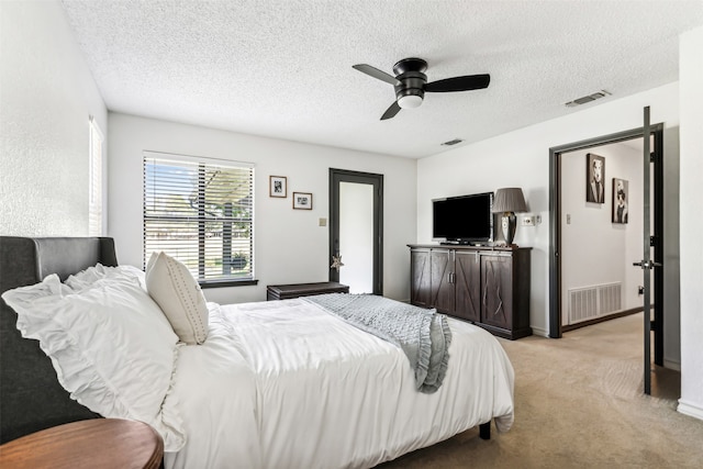 bedroom with light colored carpet, ceiling fan, and a textured ceiling