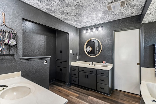 full bathroom with a textured wall, wood finished floors, and a sink