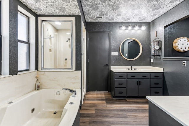 bathroom featuring wood-type flooring, a bathing tub, a textured ceiling, and vanity