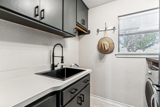 washroom featuring washer / dryer, a textured ceiling, cabinets, and sink