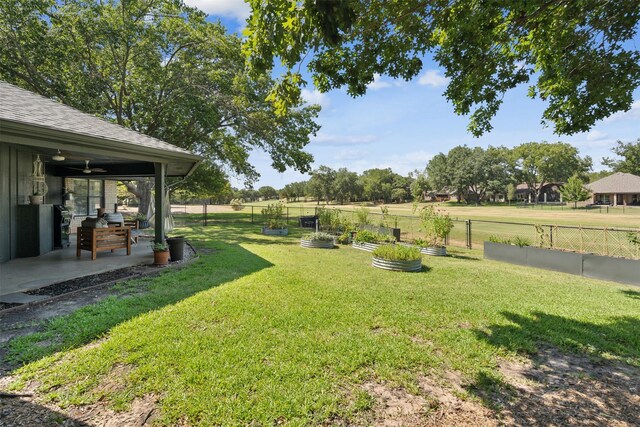 view of yard featuring ceiling fan and a rural view