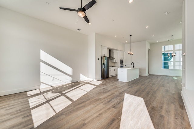 unfurnished living room with ceiling fan with notable chandelier, hardwood / wood-style flooring, and sink