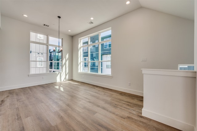 interior space with light hardwood / wood-style floors, lofted ceiling, and a chandelier