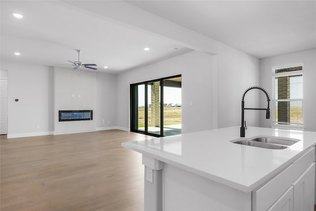 kitchen featuring light wood-type flooring, a wealth of natural light, sink, and white cabinets