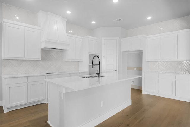 kitchen with white cabinets, premium range hood, a kitchen island with sink, and dark wood-type flooring