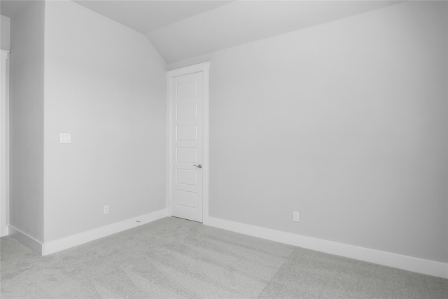 spare room featuring lofted ceiling and light colored carpet