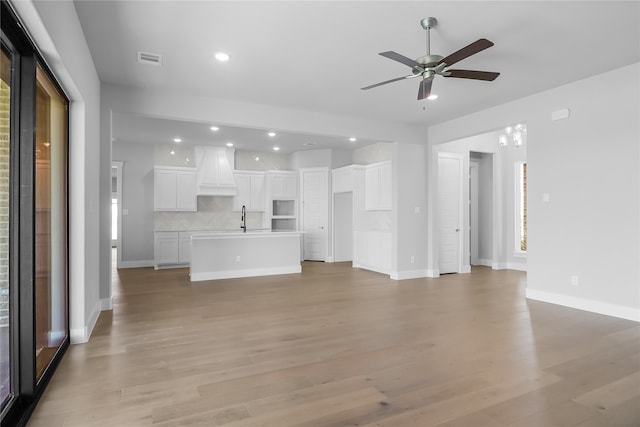 unfurnished living room with light wood-type flooring, ceiling fan, and sink