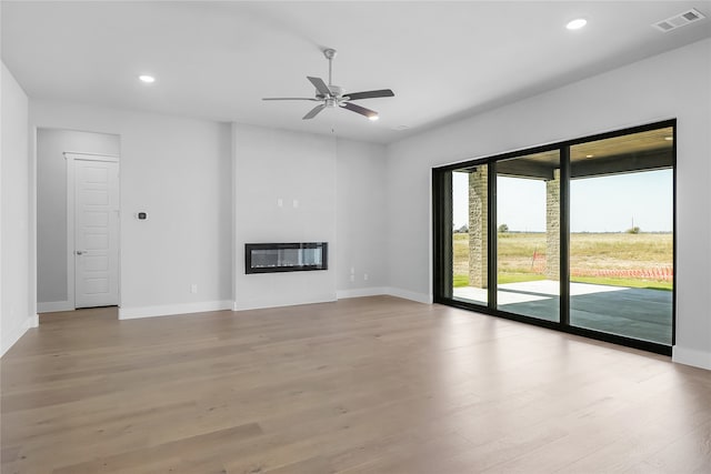 unfurnished living room with heating unit, light wood-type flooring, and ceiling fan