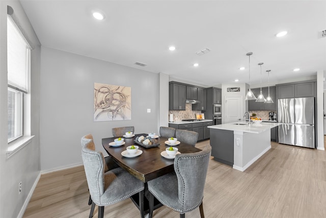 dining space featuring light wood-type flooring and sink