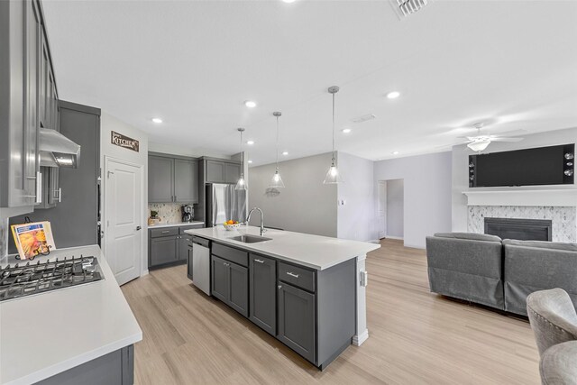 kitchen featuring gray cabinetry, sink, hanging light fixtures, extractor fan, and a kitchen island with sink