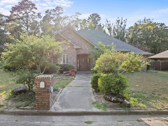 view of property hidden behind natural elements featuring a front yard