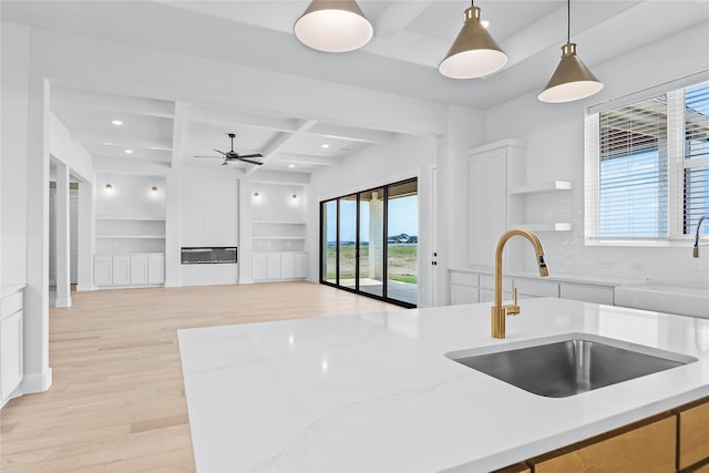 kitchen with light hardwood / wood-style flooring, sink, hanging light fixtures, and light stone counters