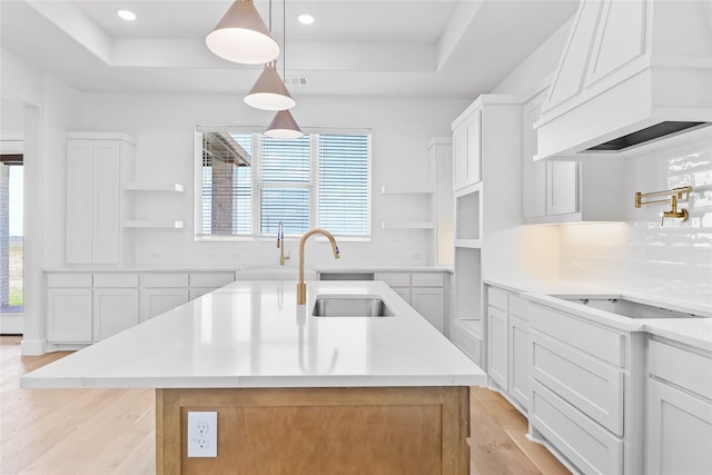 kitchen with white cabinets, a center island with sink, and plenty of natural light