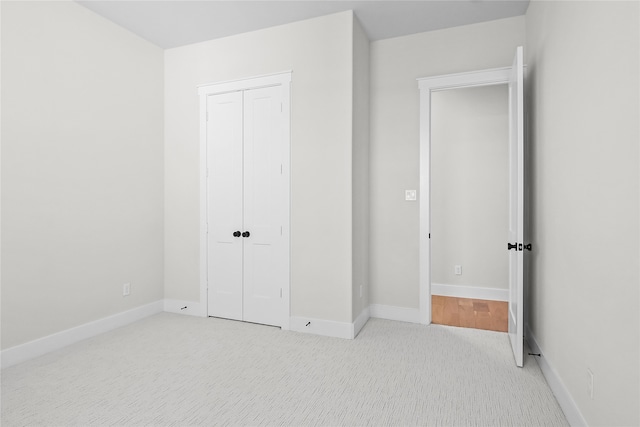 unfurnished bedroom featuring light colored carpet and a closet