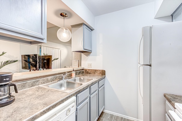 kitchen featuring sink, decorative light fixtures, white fridge, light hardwood / wood-style floors, and gray cabinetry