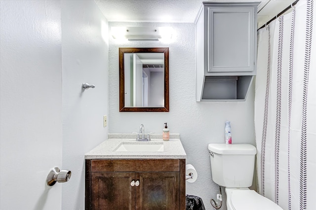 bathroom with a textured ceiling, toilet, and vanity