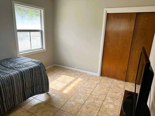 bedroom with a closet, baseboards, and light tile patterned floors