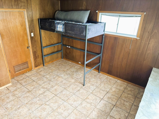 unfurnished bedroom with baseboards, tile patterned floors, visible vents, and wooden walls