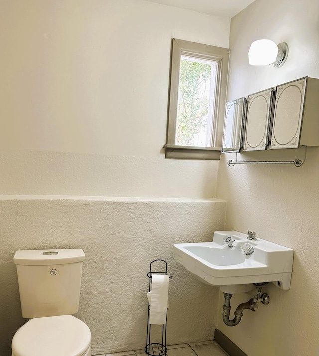 bathroom with a sink, toilet, and tile patterned floors