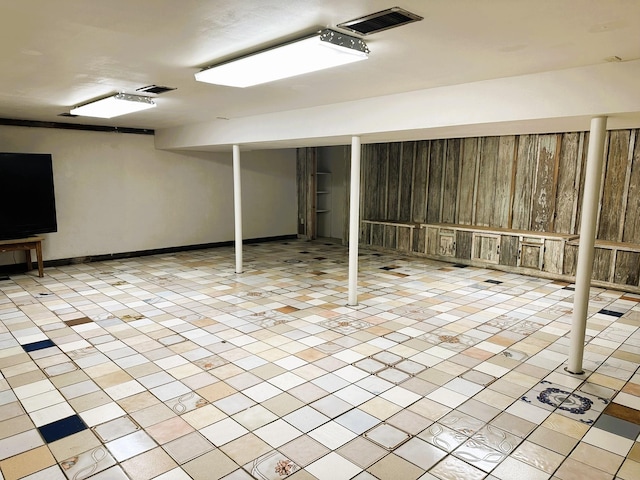 finished basement featuring baseboards, visible vents, and light tile patterned flooring