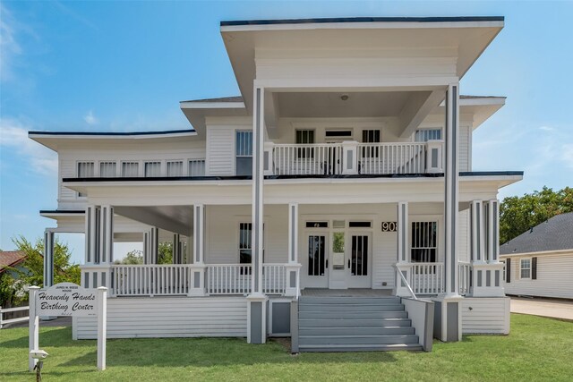 view of front of house with a balcony, covered porch, and a front yard