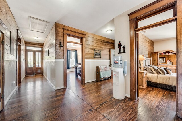 hall with attic access, wooden walls, and wood finished floors