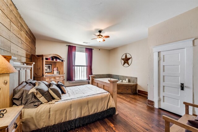 bedroom with wooden walls, a ceiling fan, baseboards, visible vents, and dark wood finished floors