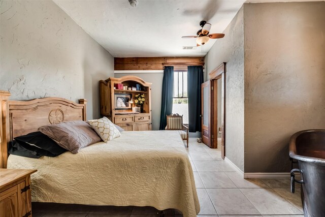 bedroom featuring light tile patterned floors, visible vents, baseboards, a textured wall, and ceiling fan