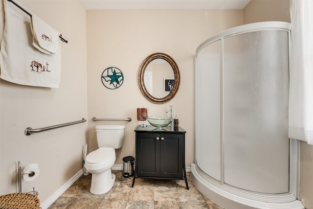 bathroom with toilet, a stall shower, baseboards, and vanity