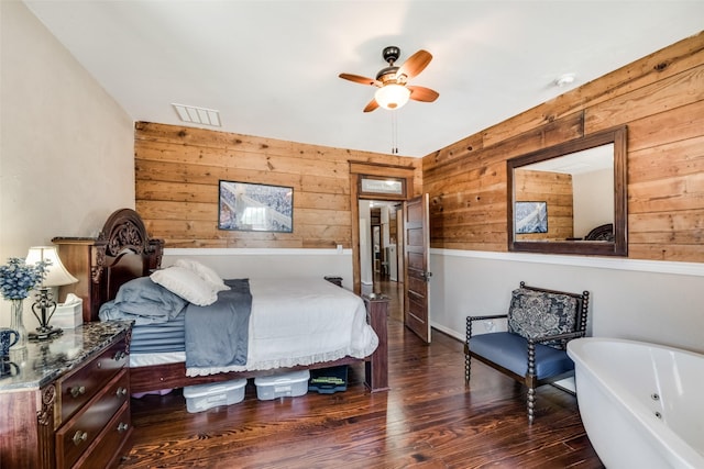bedroom featuring wood walls, visible vents, and wood finished floors