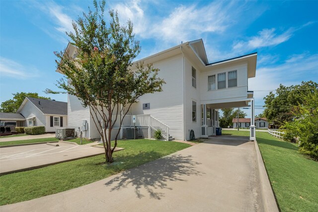 view of front of house with a carport, concrete driveway, central AC unit, and a front yard