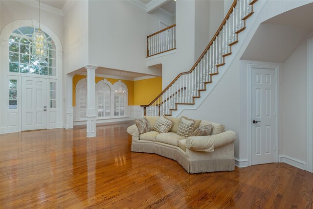 entryway with hardwood / wood-style flooring, crown molding, a high ceiling, and ornate columns