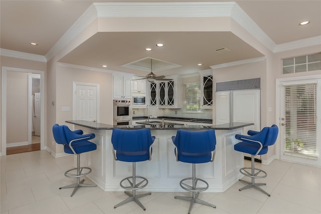 kitchen with a kitchen breakfast bar, plenty of natural light, and white cabinetry