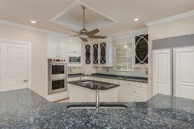 kitchen featuring dark stone countertops, ceiling fan, a raised ceiling, built in appliances, and crown molding