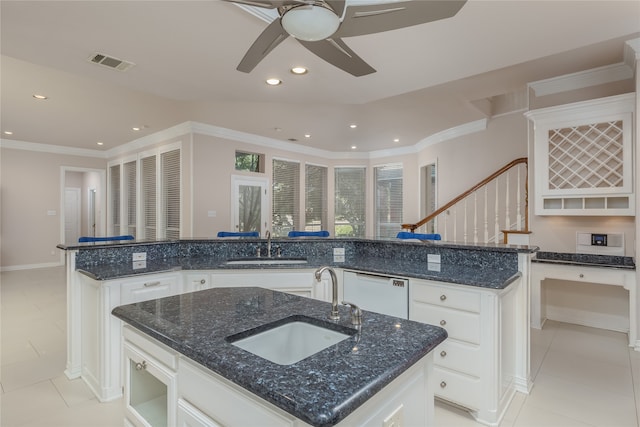 kitchen featuring dishwasher, a center island with sink, white cabinets, dark stone counters, and ceiling fan