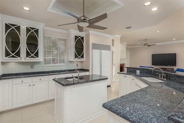 kitchen with sink, ceiling fan, an island with sink, and backsplash