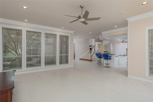 unfurnished living room with ceiling fan, light tile patterned flooring, and ornamental molding