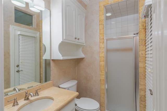 bathroom with toilet, tile walls, a shower with shower door, and vanity