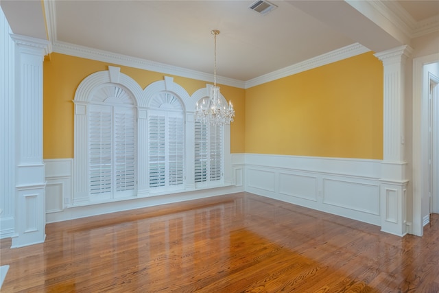 unfurnished room featuring crown molding, an inviting chandelier, decorative columns, and wood-type flooring