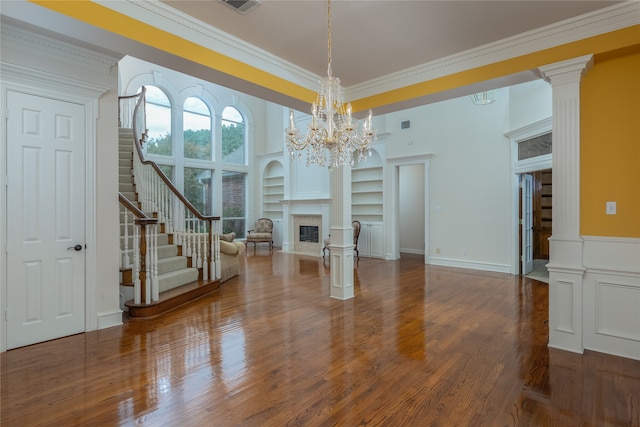 interior space featuring built in shelves, a notable chandelier, dark wood-type flooring, and ornamental molding