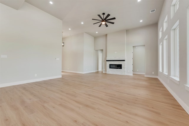 unfurnished living room with light hardwood / wood-style floors, a towering ceiling, and ceiling fan