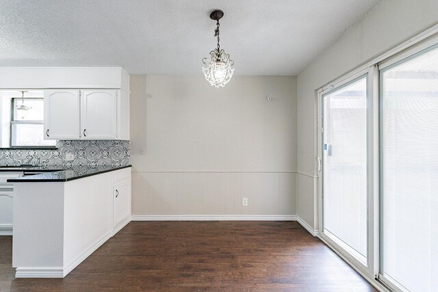 kitchen with backsplash, dark hardwood / wood-style floors, a chandelier, white cabinetry, and decorative light fixtures